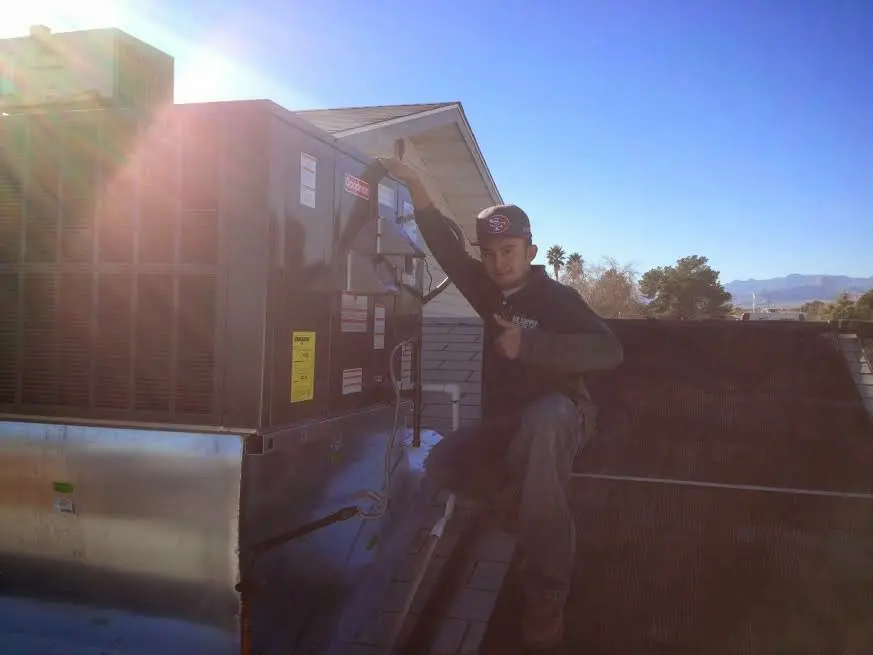 HVAC technician performing Air Duct Cleaning on a rooftop unit in Ralston